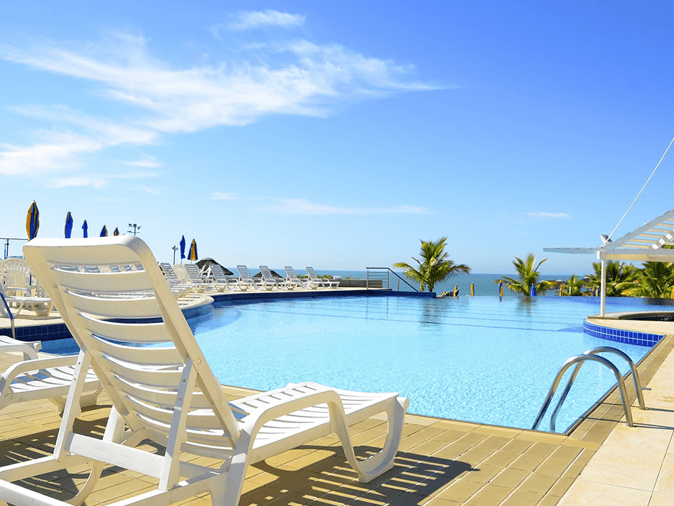 White resin pool lounge chair positioned beside a large swimming pool, demonstrating low-maintenance plastic seating for pool decks.